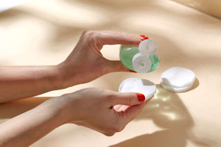 close up of hands applying lotion to cotton pad