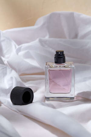 bottle of perfume and cap on white sheet