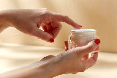 female hand holding jar of moisturizerの写真素材