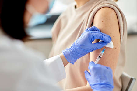 female doctor with syringe vaccinating patientの写真素材