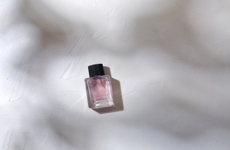 bottle of perfume on white surface with shadows