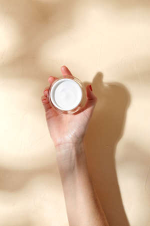 female hand holding jar of moisturizer