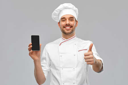 happy chef with smartphone showing and thumbs up