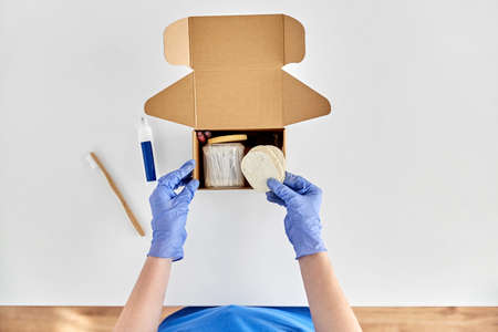 hands in gloves packing parcel box with cosmetics