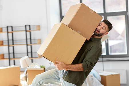 man holding heavy boxes and moving to new home