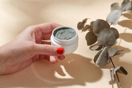 hand holding jar of blue cosmetic clay mask