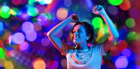 leisure, clubbing and nightlife concept - smiling young african american woman dancing in...