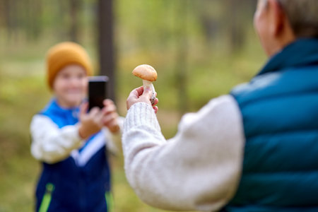 grandson photographing grandmother with mushroomの写真素材