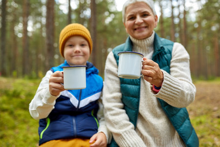 grandmother with grandson drinking tea in forestの写真素材