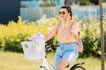 happy woman with earphones riding bicycle in city
