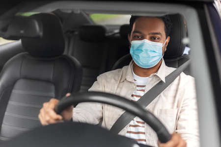 indian male driver in mask driving taxi car