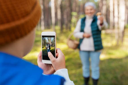 grandson photographing grandmother with mushroomの写真素材