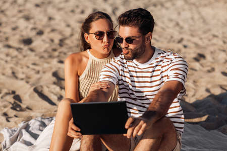 happy couple with tablet pc at on summer beachの写真素材
