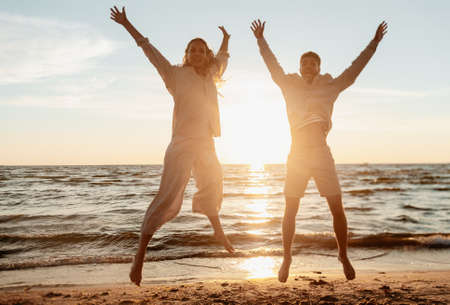 happy couple jumping on summer beach