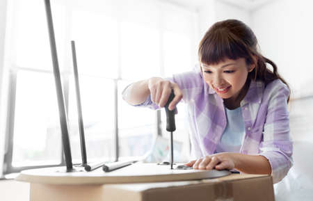 happy woman assembling coffee table at new homeの写真素材
