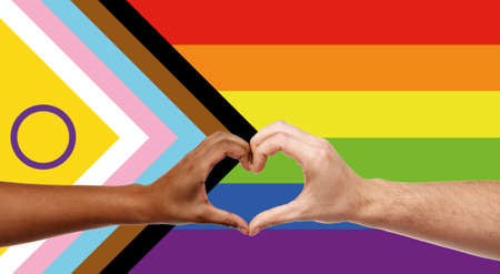 couple showing hand heart over progress pride flagの写真素材