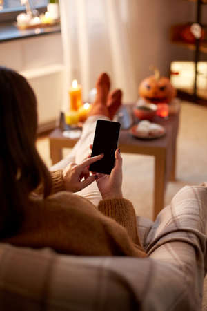 woman using smartphone at home on halloweenの写真素材