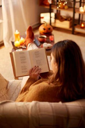 young woman reading book at home on halloween
