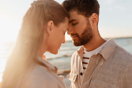 happy couple with closed eyes on summer beach