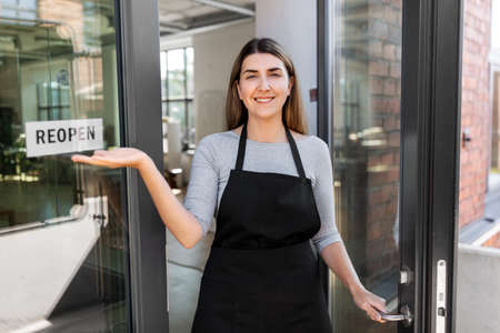 happy woman showing reopen banner on door glass