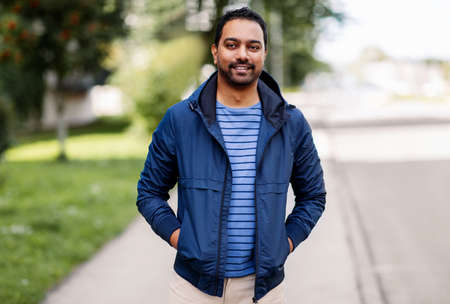 happy smiling indian man in jacket on city street