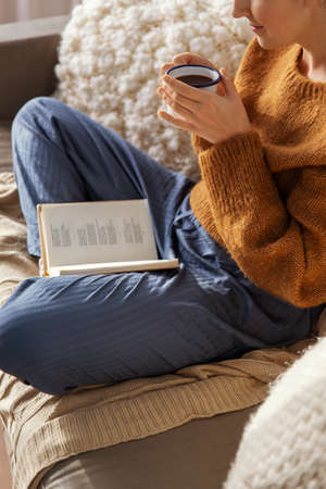 woman drinking coffee and reading book at home