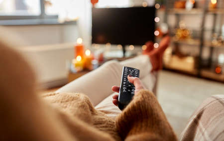 young woman watching tv at home on halloween