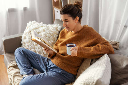 woman drinking coffee and reading book at home