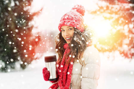 young woman with hot drink in tumbler in winterの写真素材