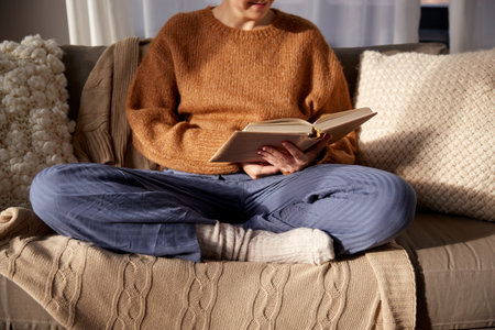 woman in warm sweater reading book at homeの写真素材