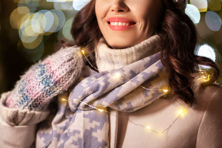 portrait of happy young woman in christmas lightsの写真素材