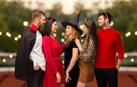 happy friends in halloween costumes at partyの写真素材