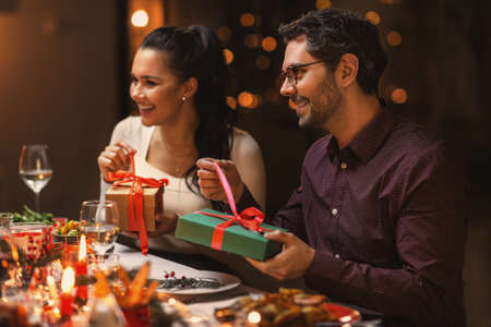 happy friends opening christmas gifts at homeの写真素材