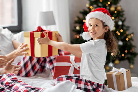 happy family with christmas gifts in bed at homeの写真素材