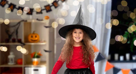 happy girl in black witch hat on halloween