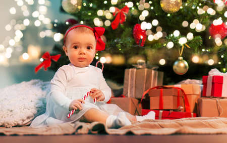 baby girl under christmas tree with gifts at homeの写真素材