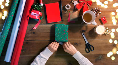 hands wrapping christmas gift on wooden tableの写真素材