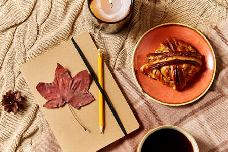 diary, cinnamon bun, coffee and candle in autumn