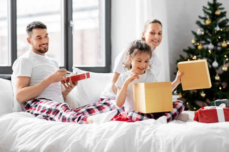 happy family with christmas gifts in bed at homeの写真素材