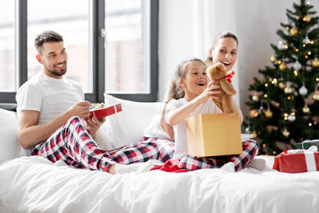 happy family with christmas gifts in bed at homeの写真素材