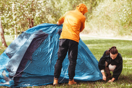 happy couple setting up tent outdoorsの写真素材
