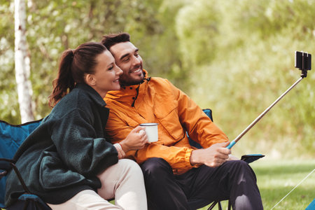 couple drinking tea and taking selfie at tent campの写真素材
