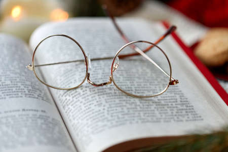 close up of open book and glasses on christmasの写真素材