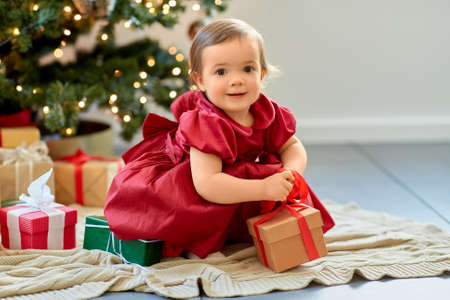 happy baby girl opening christmas gifts at homeの写真素材