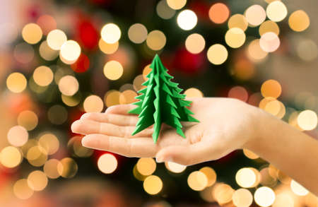 hand holding green paper origami christmas treeの写真素材