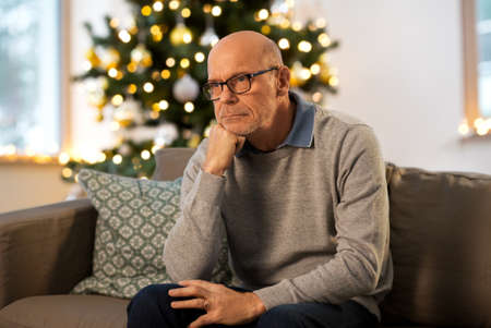 sad senior man thinking at home on christmasの写真素材