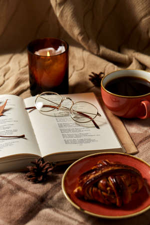 book, cinnamon bun, coffee and candle in autumnの写真素材