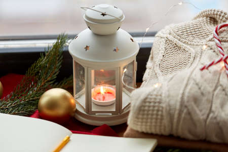 candle burning in christmas lantern and sweaterの写真素材