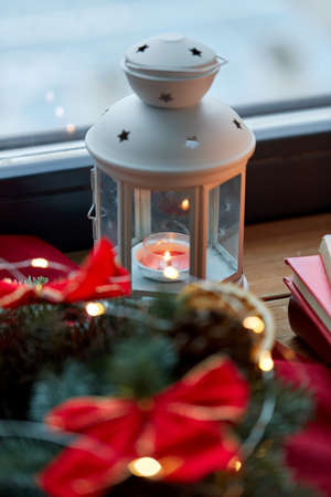 candle burning in christmas lantern on window sillの写真素材