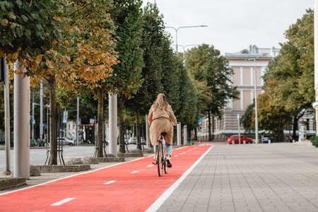 woman riding bicycle along red bike lane in cityの写真素材